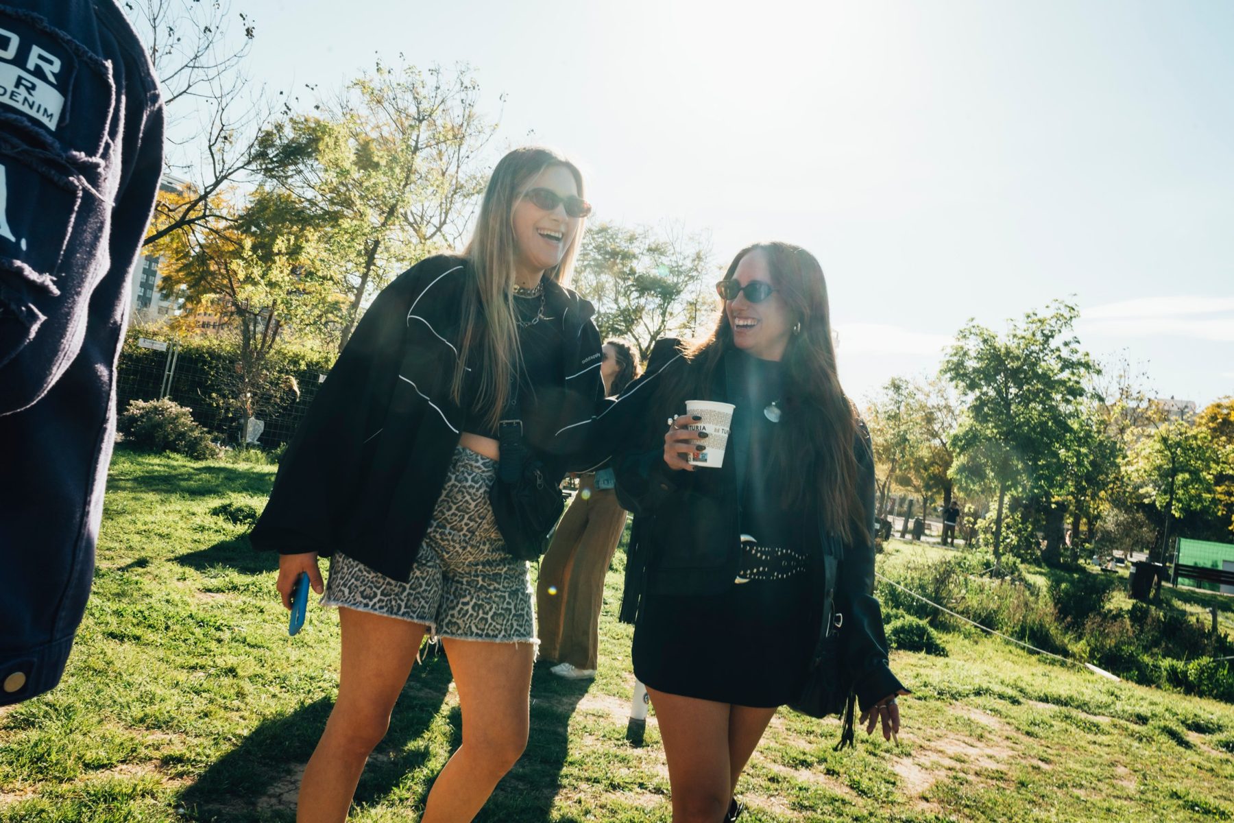 Dos amigas riendo al sol en el césped